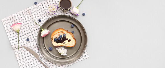 Plate with delicious blueberry jam toasts and flowers on light background with space for text