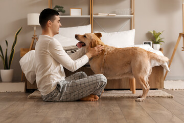 Young man with cute Labrador dog in bedroom