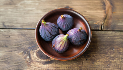 A few figs in a bowl on an old wooden background.