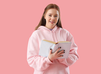 Teenage girl reading book on pink background