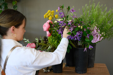 Female owner arranging flowers in pots at workshop