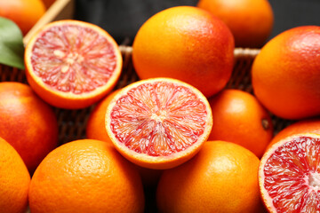 Wicker basket with tasty blood oranges on dark background