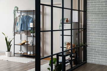 Shelving unit with clothes and accessories in interior of modern hall