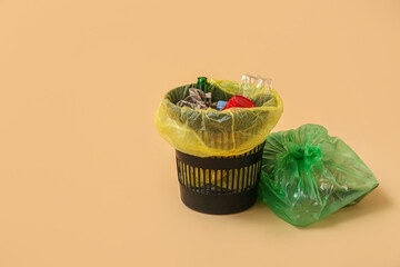 Full trash bin and garbage bag on beige background