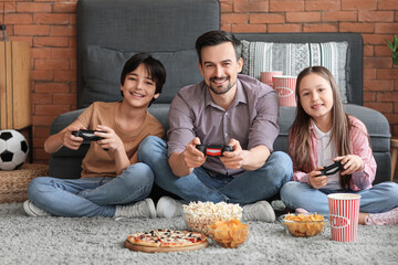 Father with his little children playing video game at home