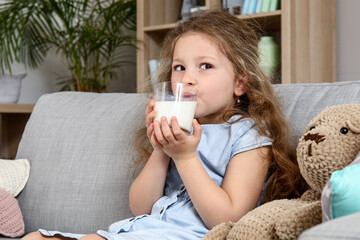 Cute little girl drinking milk at home