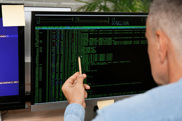 Male programmer pointing at computer monitor with command line interface, closeup