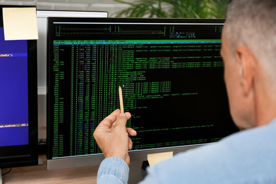 Male programmer pointing at computer monitor with command line interface, closeup