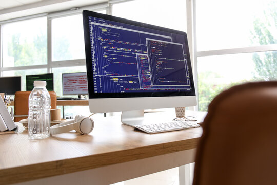 Computer monitor with programming code at programmer's workplace in office