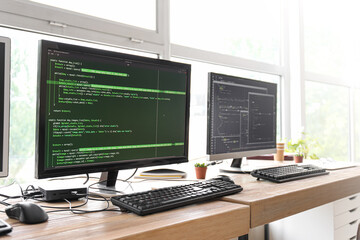Programmer's workplace with programming code on monitors in office