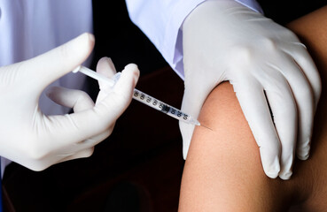 Doctor's hand using syringe to inject vaccine to patient to build immunity in body Health and...