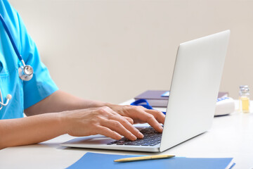 Female doctor working with laptop in clinic, closeup