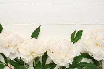 Composition with beautiful peony flowers on light wooden background, closeup