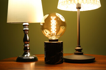 Different glowing lamps on wooden table in dark room