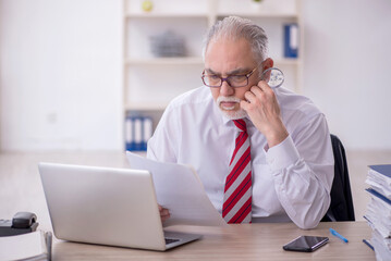 Fototapeta premium Old male employee and too much work in the office