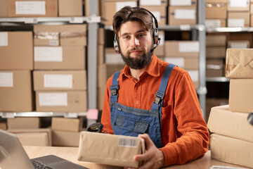 Delivery service man talking on voice picking headset and holding order, looking at camera working...