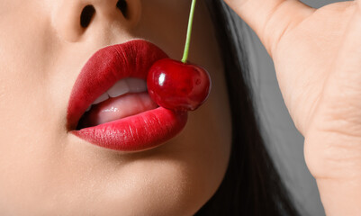 Beautiful woman with red lips and cherry on dark background, closeup - obrazy, fototapety, plakaty