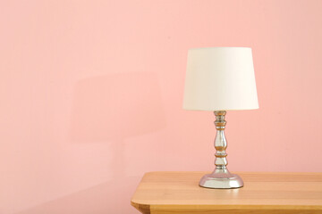 Lamp on wooden table near pink wall