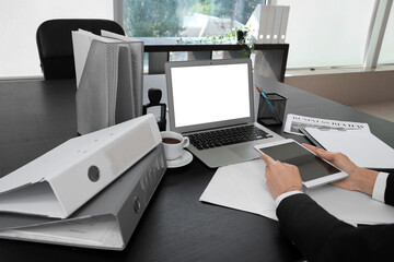 Businesswoman working with tablet computer and laptop at black table in office