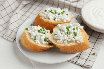 Baguette pieces with cottage cheese and green onion on plate, closeup