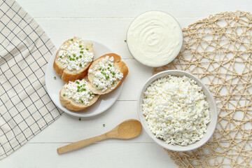 Baguette pieces with cottage cheese and sour cream on white wooden table