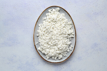 Plate with fresh cottage cheese on grey table