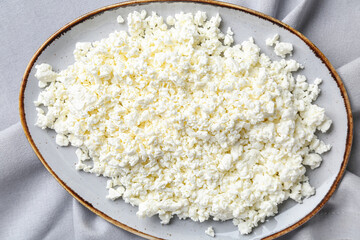 Plate with fresh cottage cheese on grey table