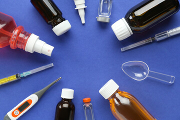 Frame made of medicine bottles, syringe, thermometer and vials on blue background