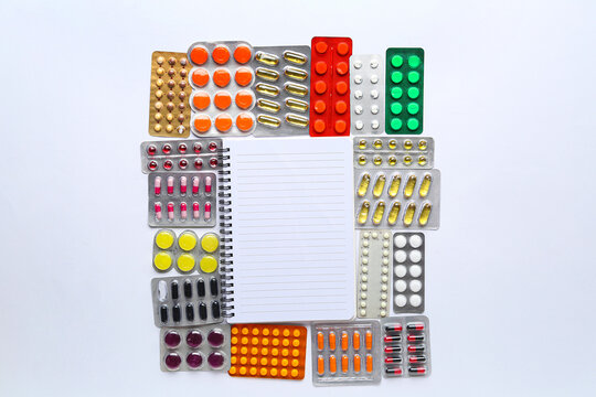 Different pills in blister packs and notebook on white background
