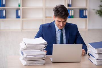 Fototapeta premium Young male employee and too much work in the office