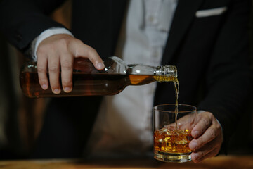 Businessman sitting and holding glass of whiskey..