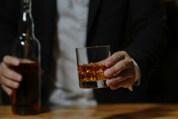 Businessman sitting and holding glass of whiskey..