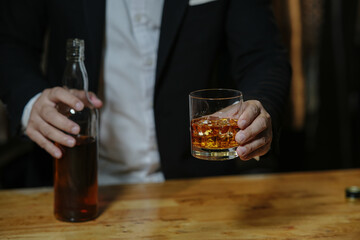 Businessman sitting and holding glass of whiskey..