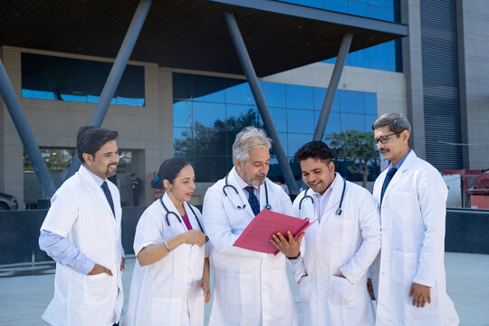 Senior doctor looking medical report and discussing to junior doctor team