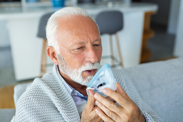 Sick elderly man making inhalation, medicine is the best medicine. Ill senior man wearing an oxygen mask and undergoing treatment for covid-19. Senior man with an inhaler