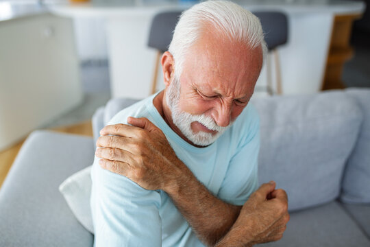 Senior elderly man touching his shoulder, suffering from shoulder pain, sciatica, sedentary lifestyle concept. shoulder health problems. Healthcare, insurance