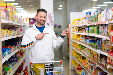 Young indian man showing direction with hand at grocery shop.