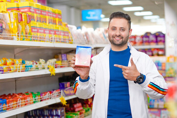Young indian man showing packets at grocery shop.