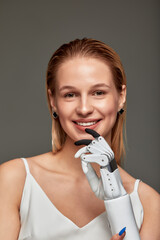 Close up studio portrait of charming young girl in white dress wearing sensory bionic prosthetic...