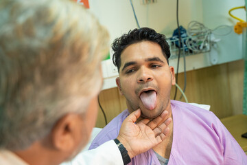 Doctor checking patient tongue between medical examination at hospital. - Powered by Adobe