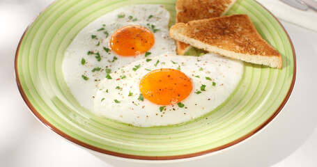 fried eggs with toast on a green plate. close-up. angle view. camera tracking. white background. traditional breakfast. sunny day.