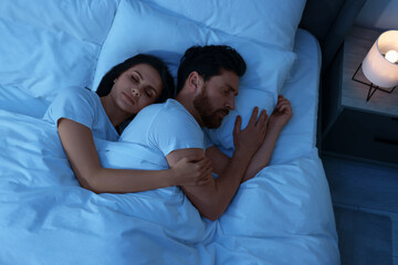 Lovely couple sleeping together in bed at night, top view