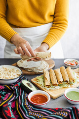 Mexican woman cooking tacos dorados called flautas with chicken, traditional fried food in Mexico Latin America