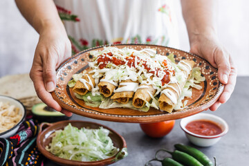 Mexican woman cooking tacos dorados called flautas with chicken, traditional fried food in Mexico Latin America