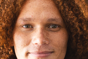 Portrait of happy biracial man with curly red hair and freckles smiling - Powered by Adobe