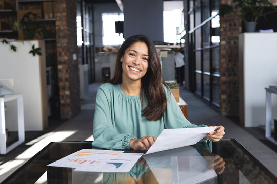 Portrait of happy biracial casual businesswoman having video call with document in office