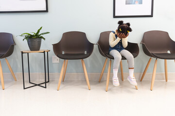 Sad african american girl patient sitting in waiting room at hospital, copy space