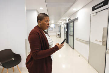 Fototapeta na wymiar Worried african american female patient using smartphone in waiting room at hospital