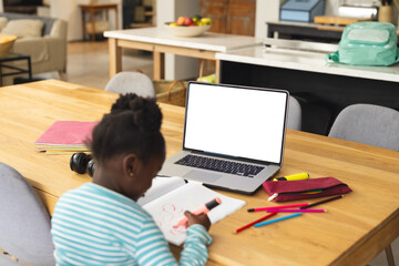African american girl sitting at table using laptop with copy space for online lesson