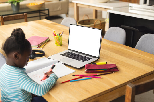 African american girl sitting at table using laptop with copy space for online lesson